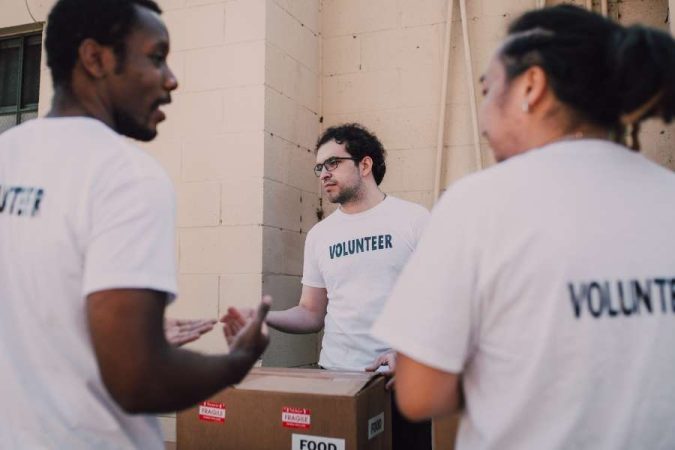 Des bénévoles en t-shirts blancs organisent des boîtes de nourriture pour le volontariat international.