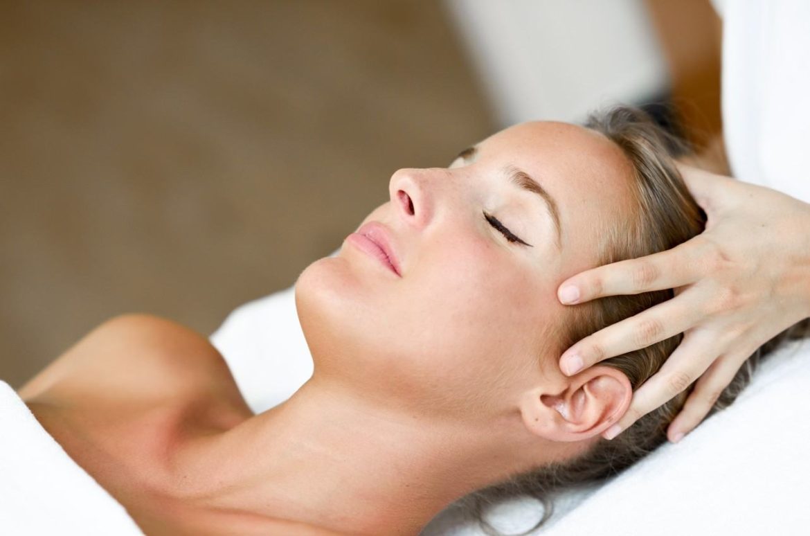 Une femme aux yeux fermés recevant un massage crânien pour apaiser ses migraines et tensions au niveau des tempes.